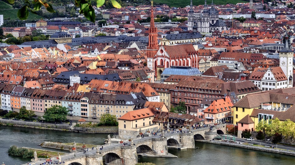 Eine Altstadt mit mehreren Kirchtürmen an einem Fluss. 