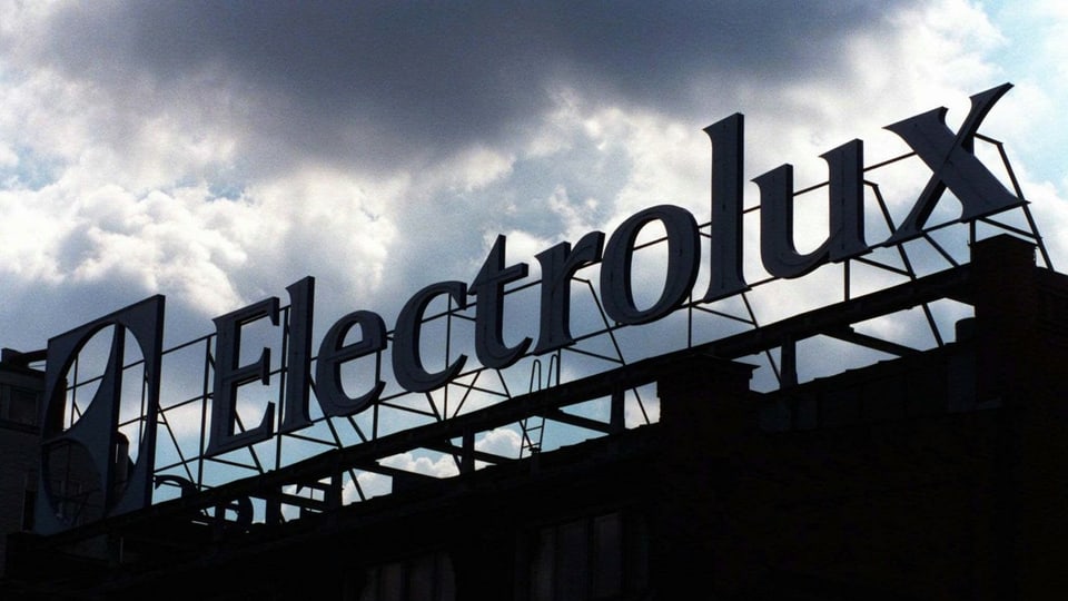 Electrolux-Schriftzug auf einem Fabrikgebäude, dunkle Wolken ziehen vorüber.
