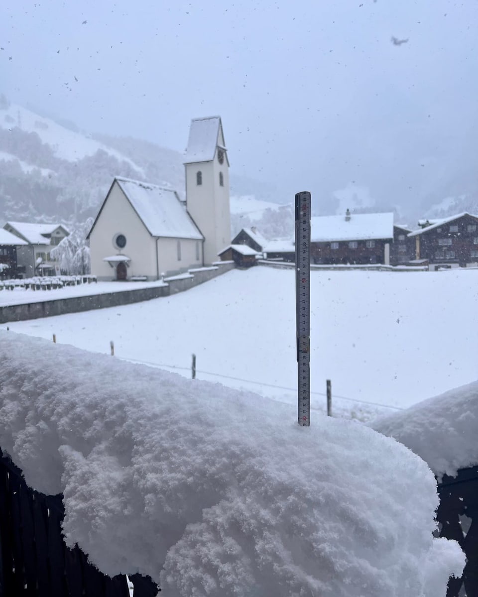 Schneelandschaft mit Kirche und Messstab in Vordergrund