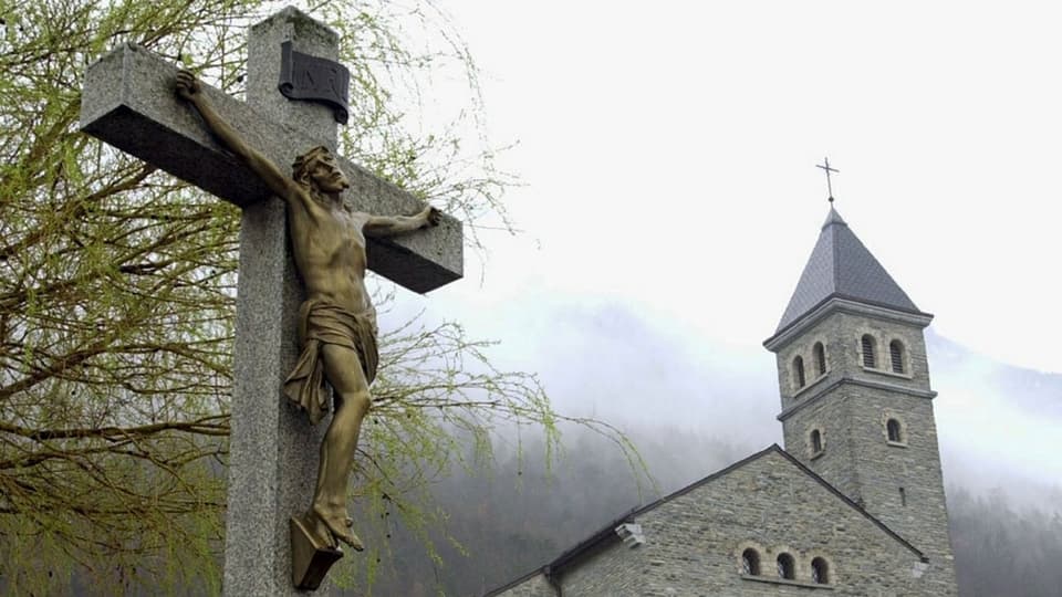 Jesus-Figur am Kreuz vor einer Kirche.