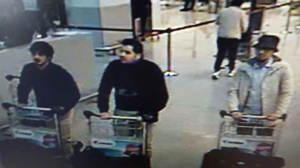 Drei Männer mit Gepäck auf dem Bild einer Überwachungskamera