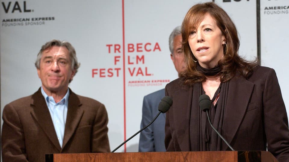 CEO Jane Rosenthal spricht anlässlich des Tribeca Film Festival; Robert De Niro hört im Hintergrund zu.