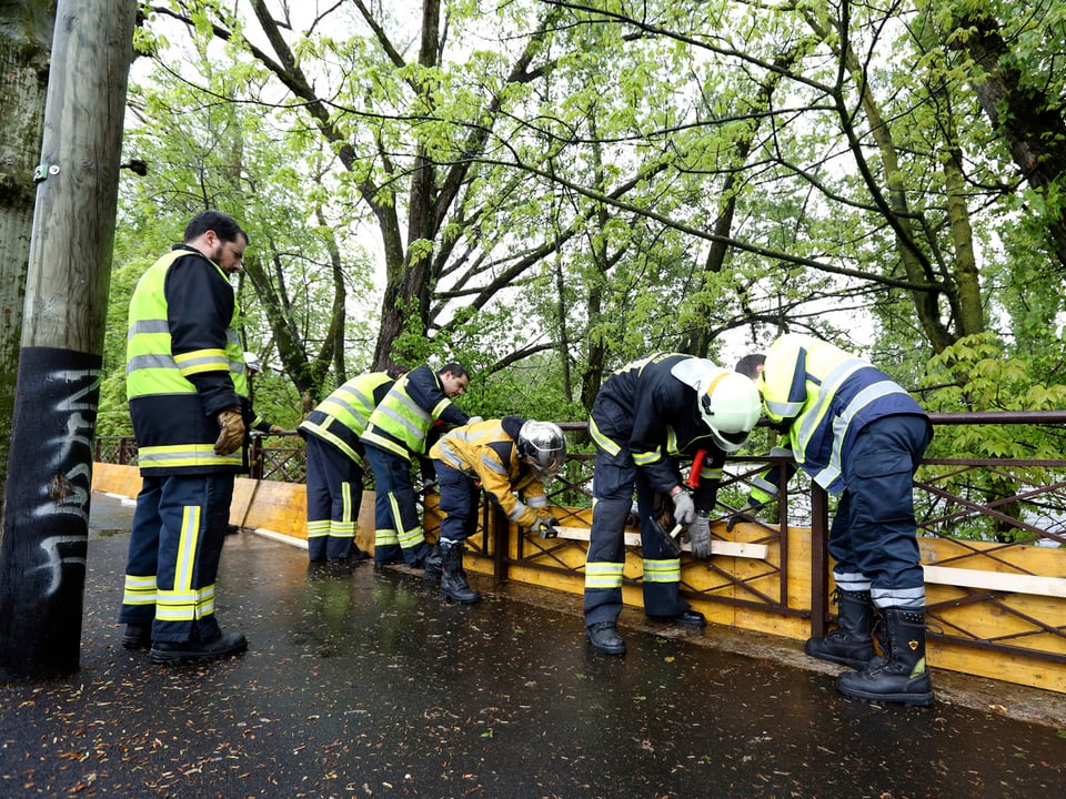 Feuerwehrmänner befestigen Holzbretter an einer Brücke.