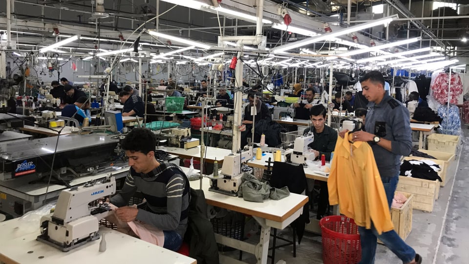 Junge Männer in einer Textilfabrik an Nähmaschinen
