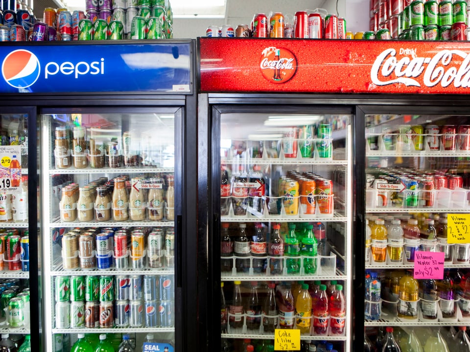 Kühlschränke mit Glastüren mit verschiedenen Getränkeflaschen und den Logos von Pepsi und Coca-Cola.
