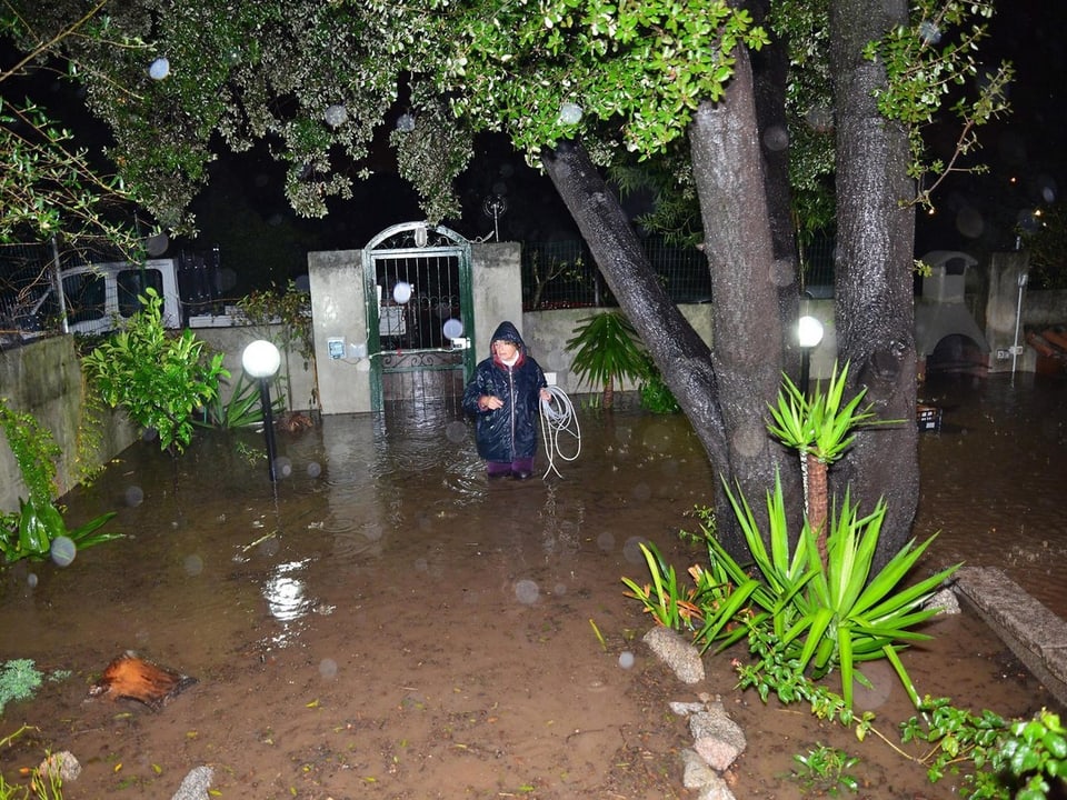 Eine Frau steht in ihrem überfluteten Garten.