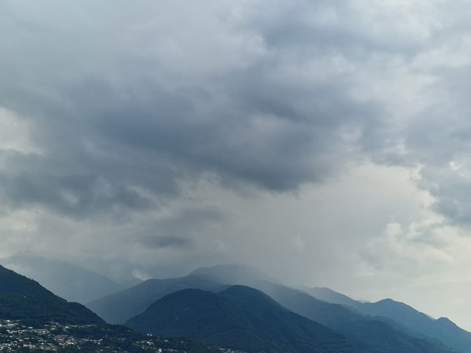 Dunkle Wolken über den Bergen am Abend von Locarno aus gesehen.