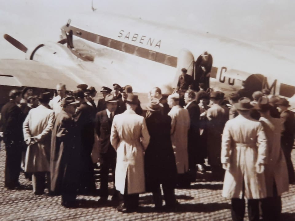Auf einem historischen Foto warten Männer vor einem Flugzeug.