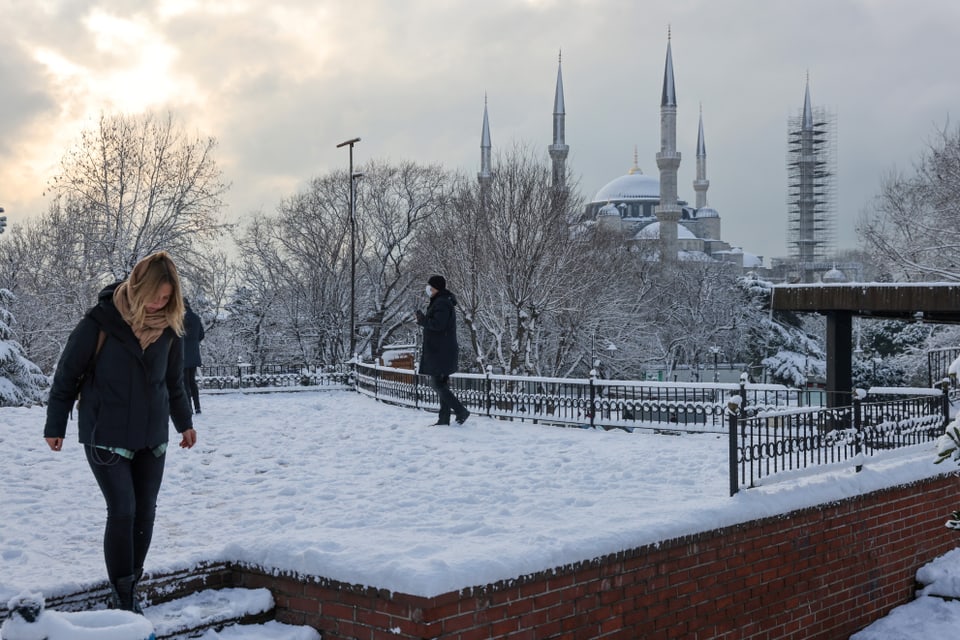 Eine Touristin vor der verschneiten Ahmet Moschee in Istanbul