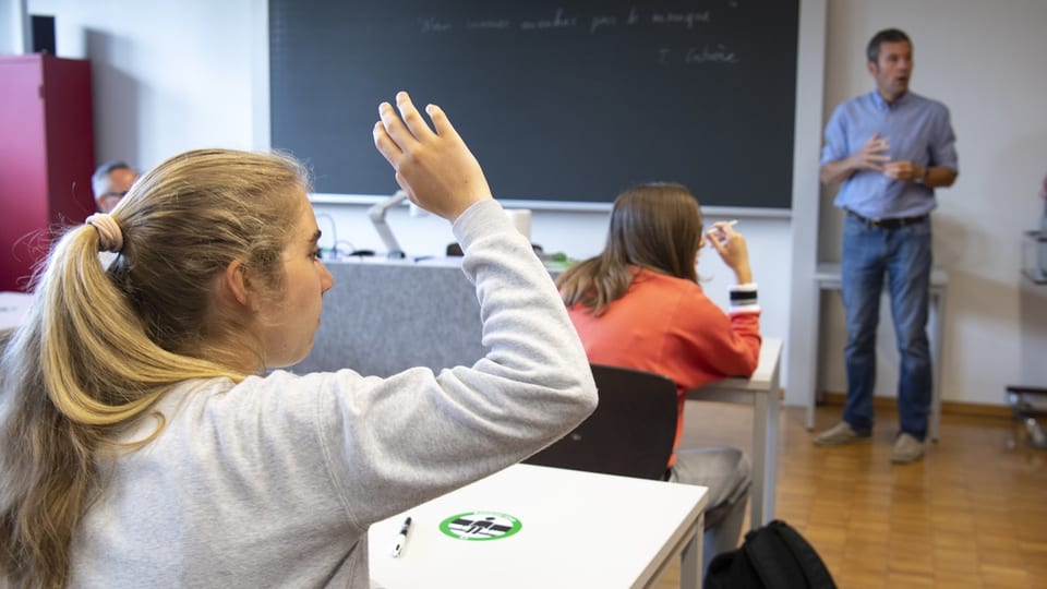Eine Schülerin hebt die Hand, um etwas zu sagen.