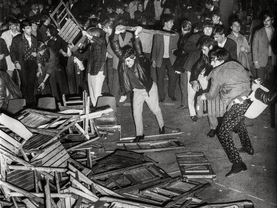 Leute werfen Stühle an einem Konzert 1967 zu Boden.