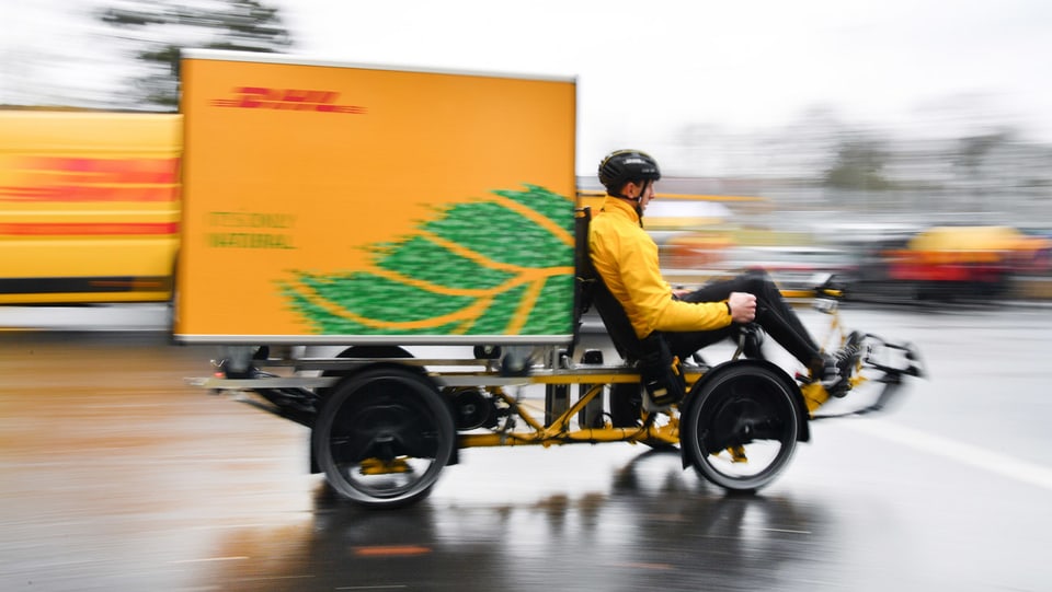 Ein DHL-Kurierfahrer ist mit einem Cargobike unterwegs.