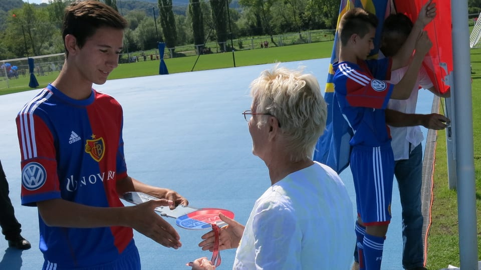 Gigi Oeri übergibt einen rotblauen Schlüssel an einen Nachwuchsspieler im FCB-Dress.