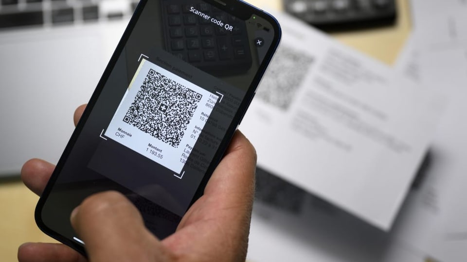 Ein Handy scanned einen QR-Code einer Rechnung. Handy in einer Nahaufnahme. 