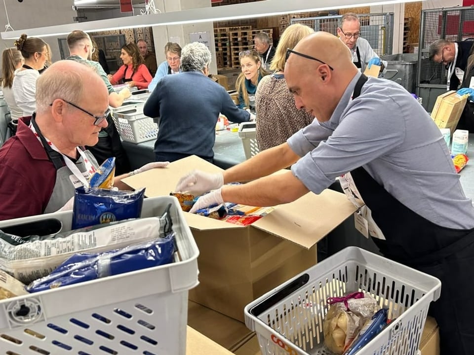 Tausende Pakete stapeln sich in der Halle in Wabern bei Bern, Freiwillige packen die Spenden aus den Paketen aus