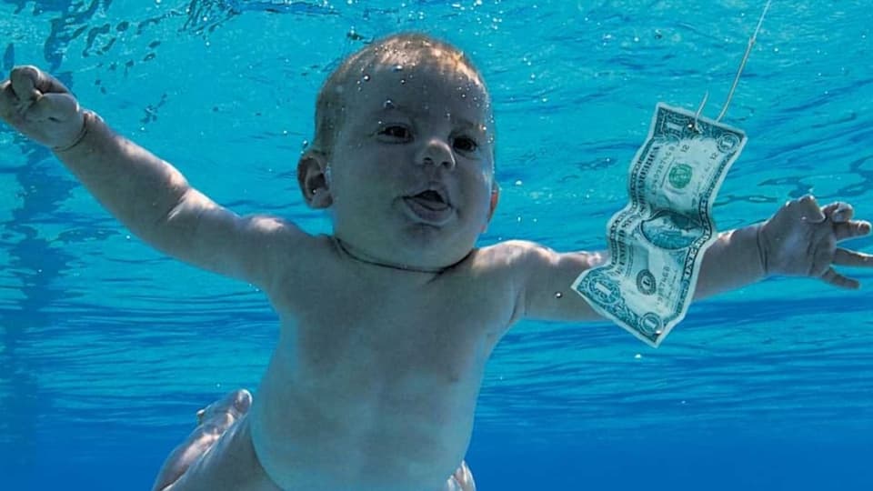 Ein nacktes Baby taucht unter Wasser einer 1-Dollar-Note nach.