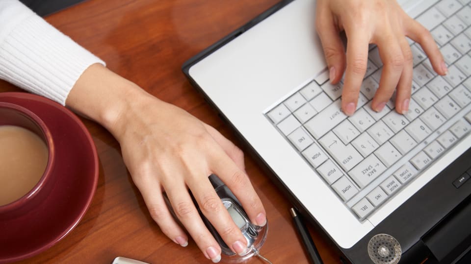 Frauenhände auf Laptoptastatur.