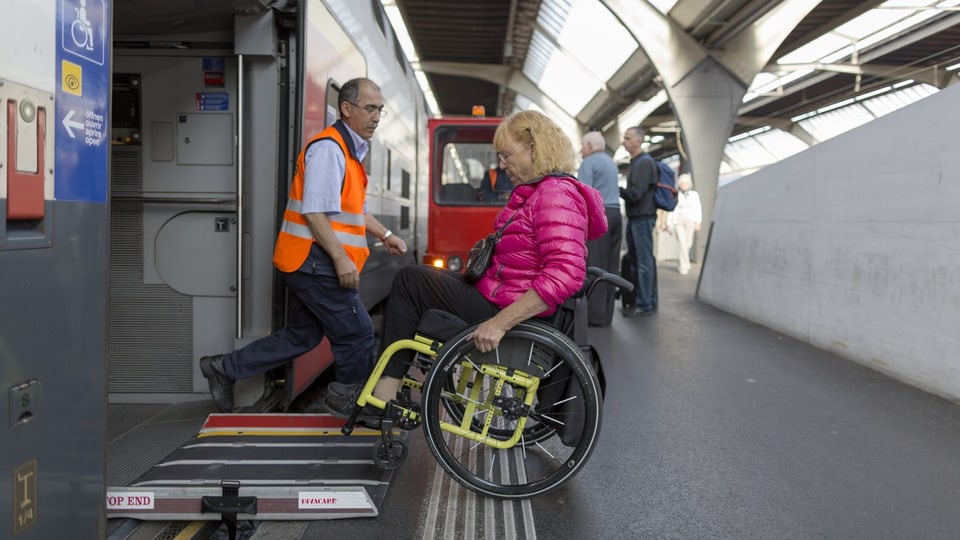 Frau fährt mit Rollstuhl über eine Rampe in den Zug hinein.
