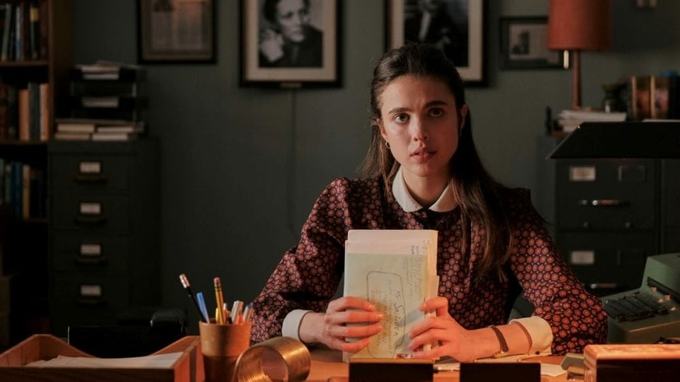 Eine junge Frau sitzt mit einem Bündel Notizen in den Händen an einem Pult.