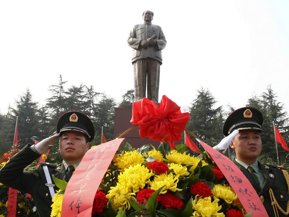 Eine Statue von Mao, im Vordergrund zwei Soldaten.