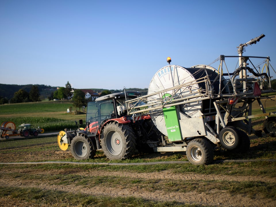 Ein Traktor fährt auf einer trockenen Landwirtschaftswiese 