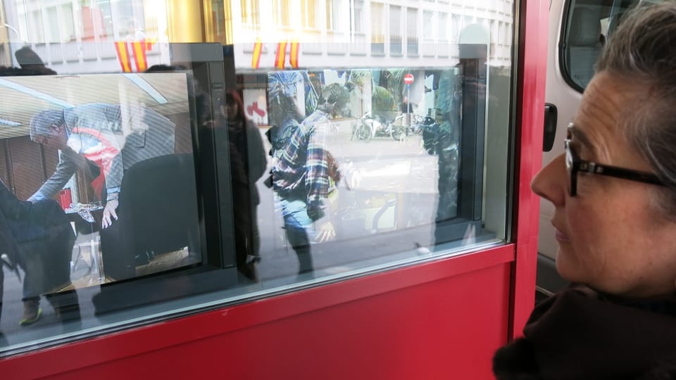 Eine Frau schaut auf zwei Fernsehbildschirme in einem Schaufenster.