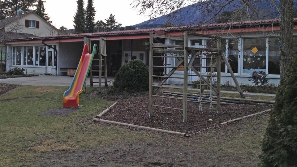Kindergartengebäude mit Spielplatz (Rutschbahn) im Vordergrund