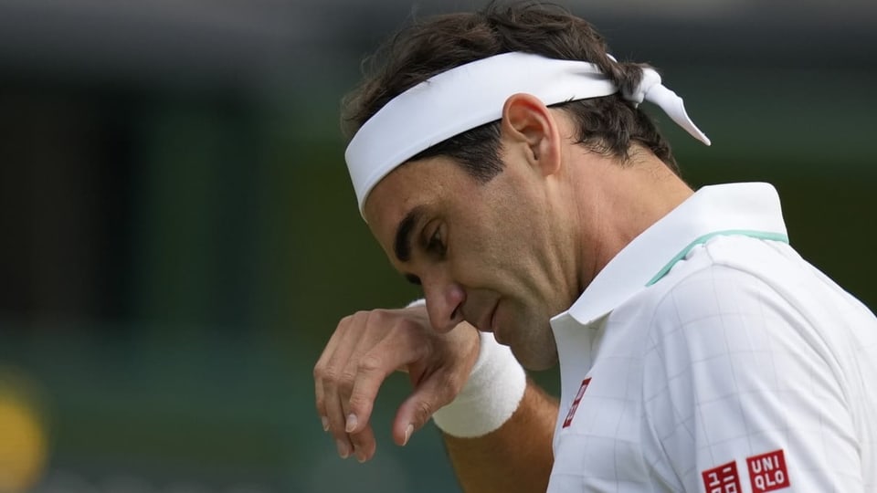 Roger Federer wischt sich den Schweiss aus der Stirn.