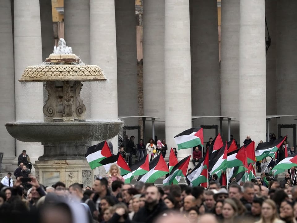 Menschen halten auf dem Petersplatz palästinensische Flaggen in die Höhe