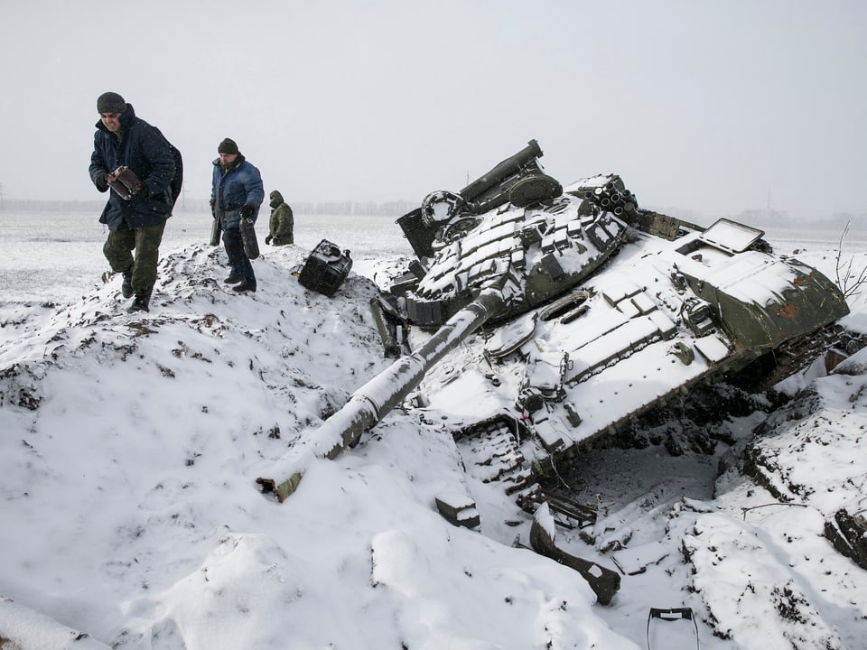 Soldaten in der Ukraine neben einem kaputten Panzer 