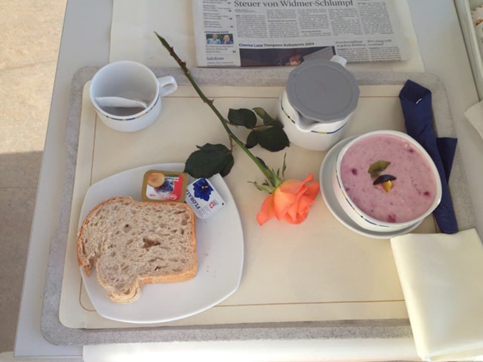 Frühstückstablet im Spital mit einem Stück Brot, Butter, Konfitüre und Müesli.