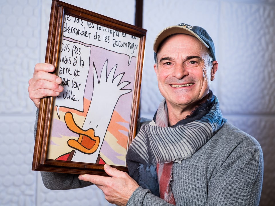 Sprecher Hans-Georg Panczak mit einem Bild der Comic-Figur Herbert, einem weissen Vogel.