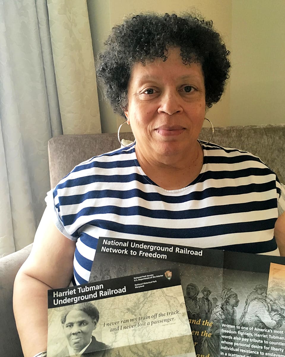 Eine Frau hält zwei Leaflets in die Kamera, die von der US-amerikanischen Sklavengeschichte berichten. 
