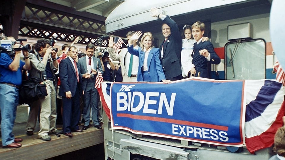 Wagen eines Zuges, ein Plakat Biden-Express. Die Familie winkt.
