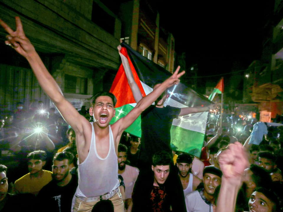Ausgelassene Menschenmenge feiert und hält Palästina-Flaggen hoch