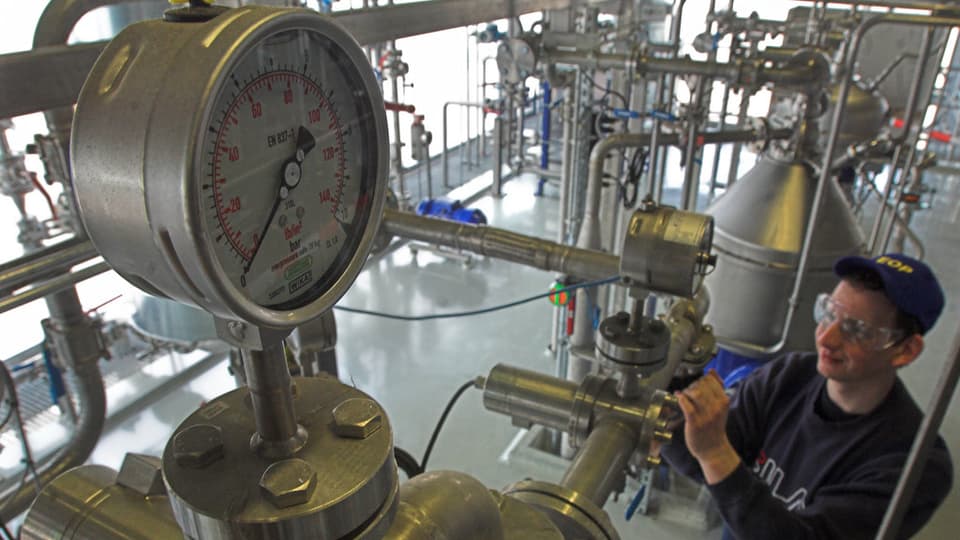 Arbeiter einer Biodieselfabrik bedient ein Ventil.