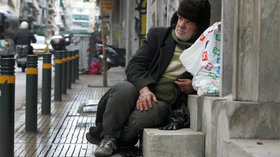Ein Obdachloser sitzt in einem Hauseingeng.