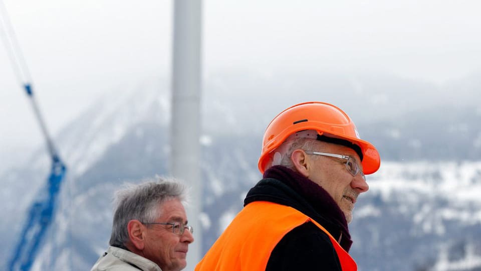 Zwei Männer mit Bauhelm vor dem Windrad
