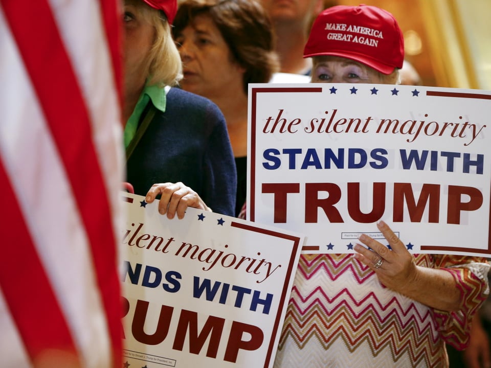 Trump-Fans halten Schilder hoch mit der Aufschrift "Die schweigende Mehrheit steht zu Trump"