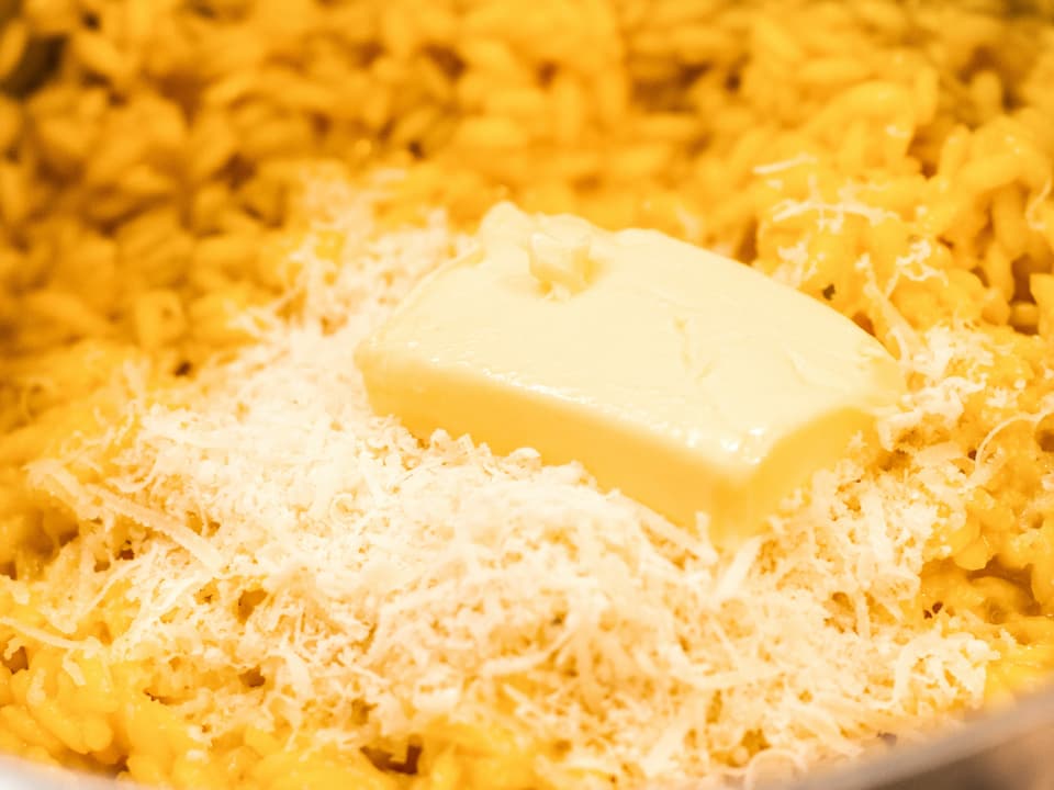 Butter und geriebener Käse wird in den Safran-Risotto eingerührt. 