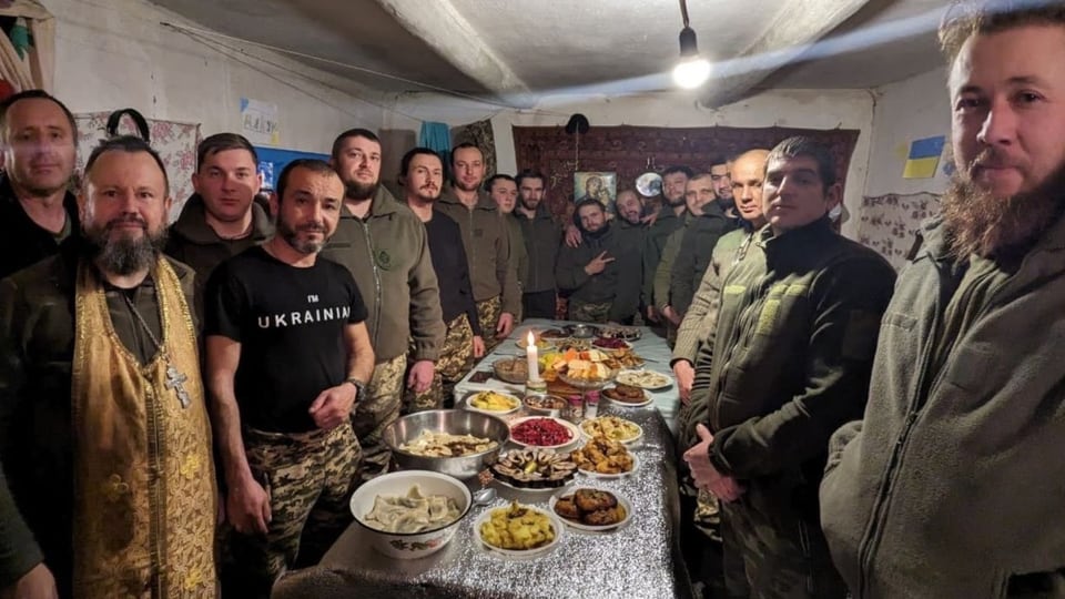Soldaten stehen um einen Tisch mit zahlreichen Speisen.