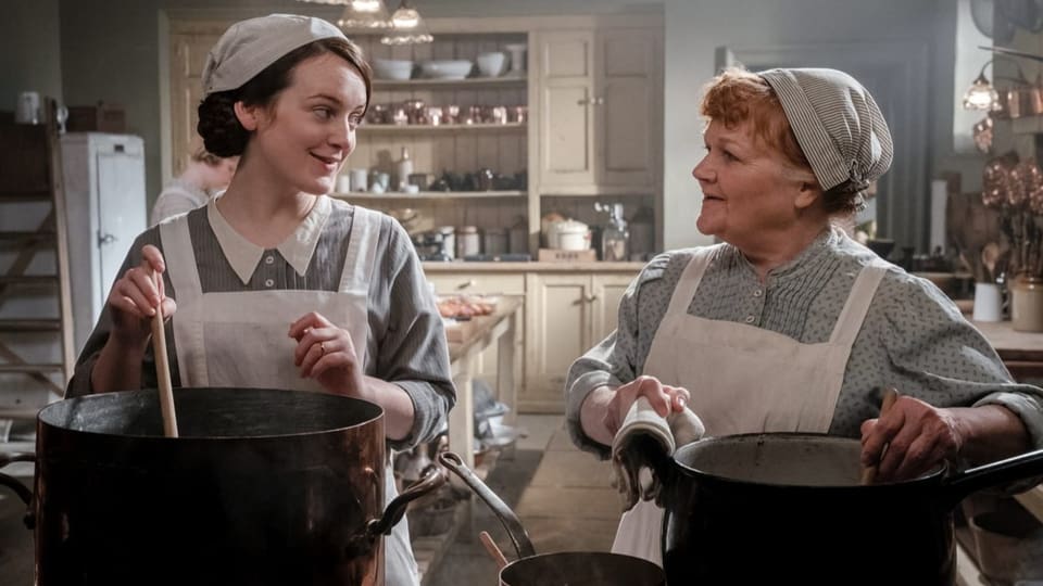 Filmszene: Zwei Frauen stehen nebeneinander in der Küche und rühren in Töpfen.