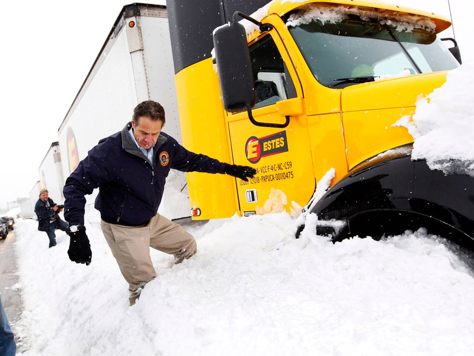 Mann über Schneehaufen steigend. Daneben steht ein Lastwagen.