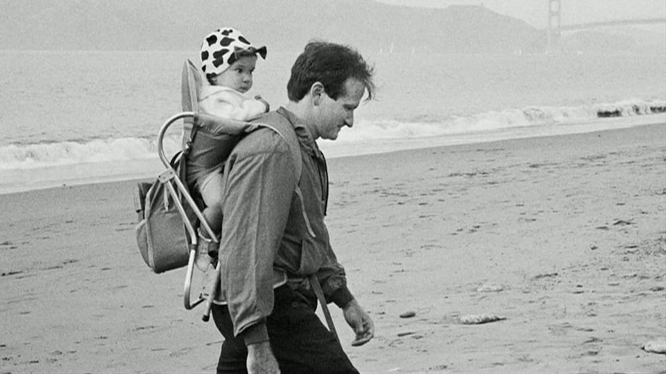 Williams mit Kleinkind auf Rücken am Strand