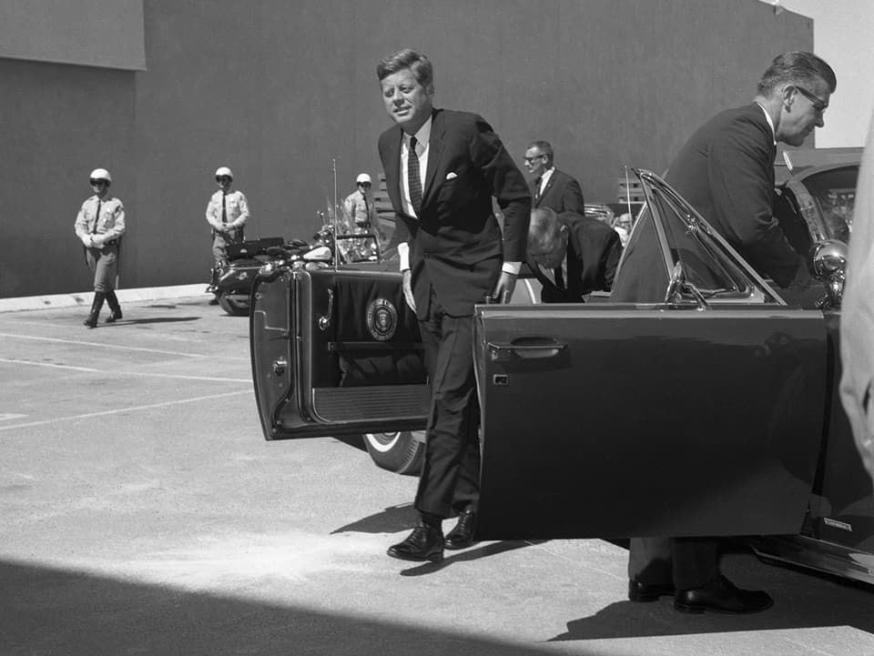 John F. Kennedy steigt aus einem Auto.