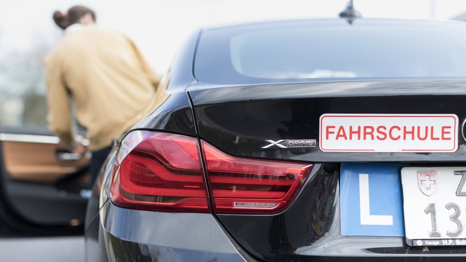 Junger Neulenker steigt in Fahrzeug einer Fahrschule.