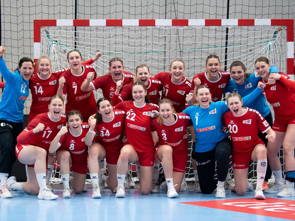 Jubelnde Schweizer Handballerinnen posieren vor dem Tor.