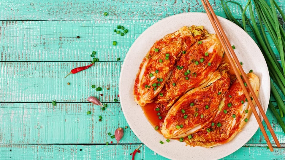 Kimchi auf einem Teller mit Stäbchen.