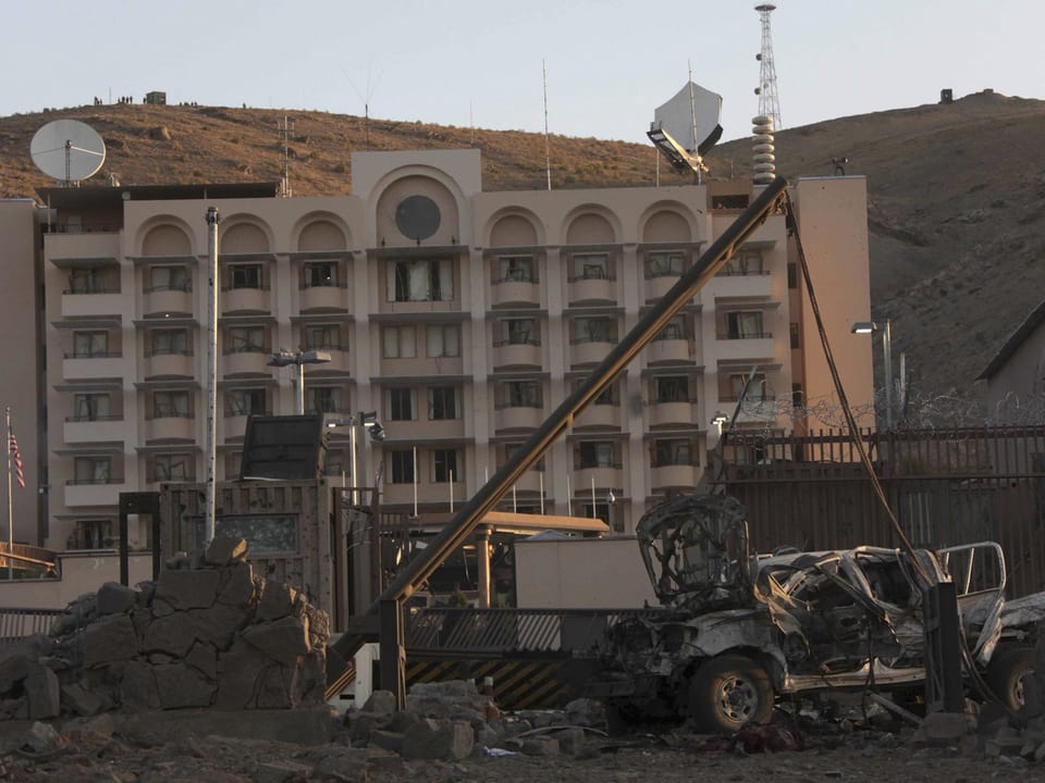 Explodierter Jeep im Vordergrund - im Hintergrund das nicht zerstörte Konsulat.