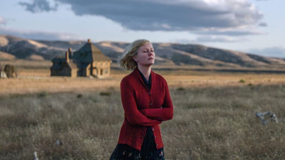 Frau mit rotem Strickmantel in einer Steppenlandschaft.